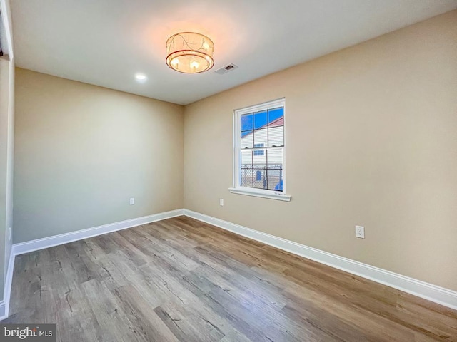 unfurnished room with visible vents, light wood finished floors, and baseboards