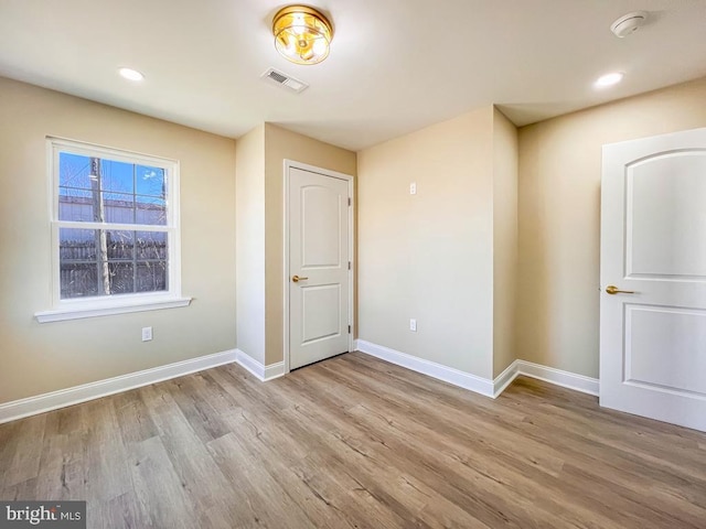 empty room with recessed lighting, light wood-type flooring, visible vents, and baseboards