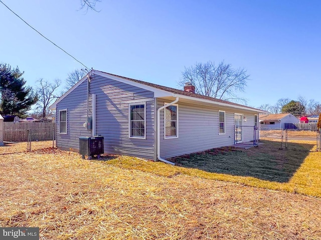 view of home's exterior featuring a yard, fence, a chimney, and central AC unit