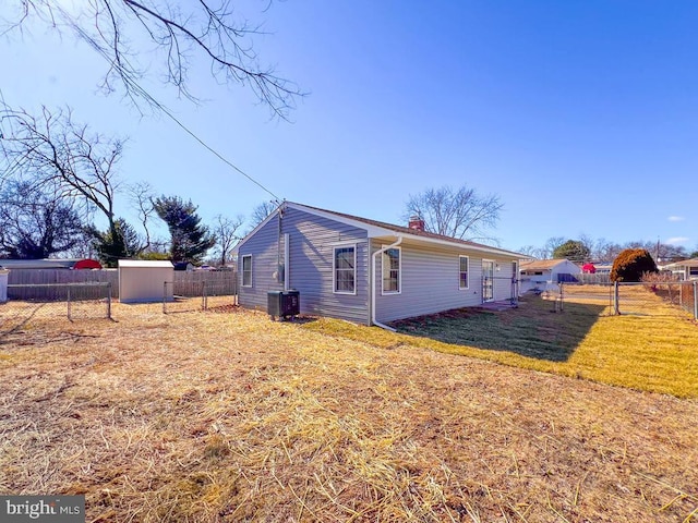 view of property exterior featuring a fenced backyard, a chimney, an outbuilding, a storage unit, and a yard