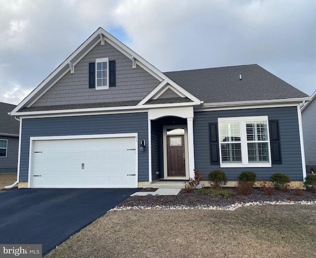 view of front of home with driveway, a shingled roof, and a garage