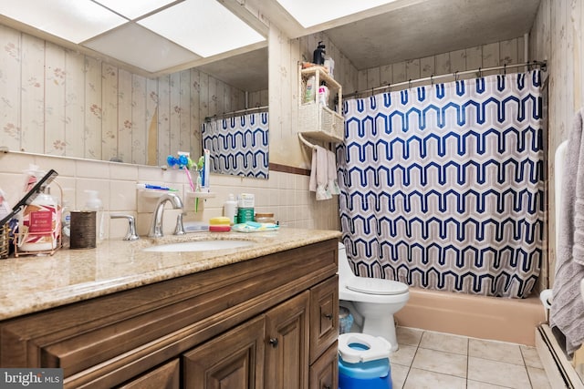 full bath with a baseboard radiator, tile patterned flooring, toilet, vanity, and tile walls