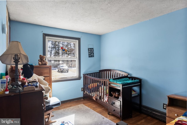 bedroom with a textured ceiling, baseboards, and wood finished floors