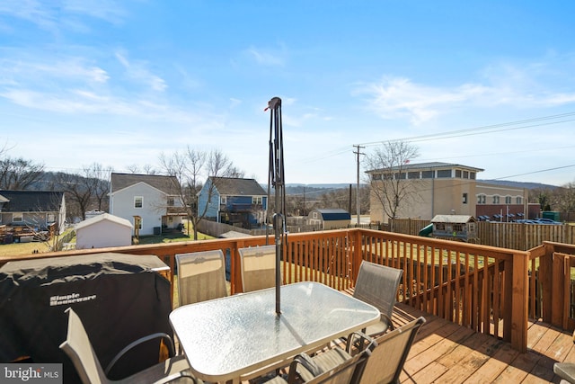 deck featuring outdoor dining space, a grill, a residential view, and fence