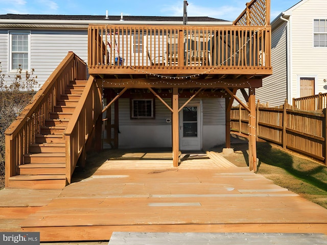 back of property featuring fence, a wooden deck, and stairs