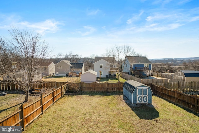 view of yard with an outbuilding, a storage unit, a fenced backyard, and a residential view