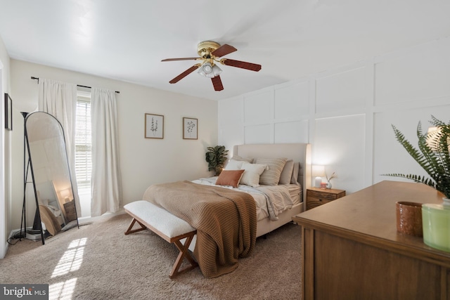 bedroom with a ceiling fan, a decorative wall, and carpet flooring