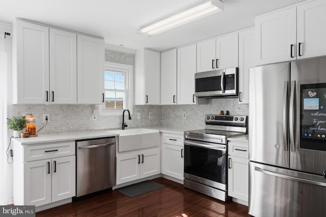 kitchen with stainless steel appliances, dark wood-type flooring, a sink, white cabinets, and light countertops