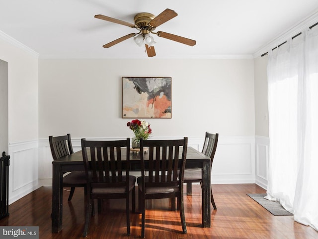 dining room with a decorative wall, wainscoting, dark wood finished floors, and crown molding