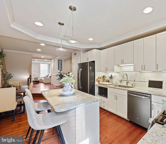 kitchen featuring hanging light fixtures, appliances with stainless steel finishes, a sink, and white cabinetry