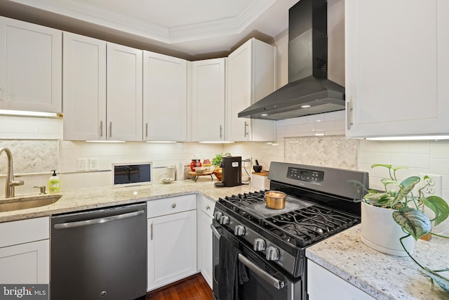 kitchen with wall chimney range hood, white cabinets, stainless steel dishwasher, and gas range