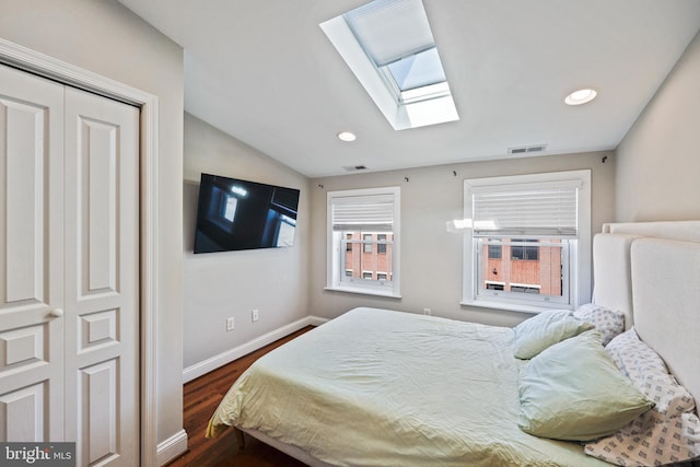 bedroom with dark wood-style floors, baseboards, visible vents, and lofted ceiling with skylight