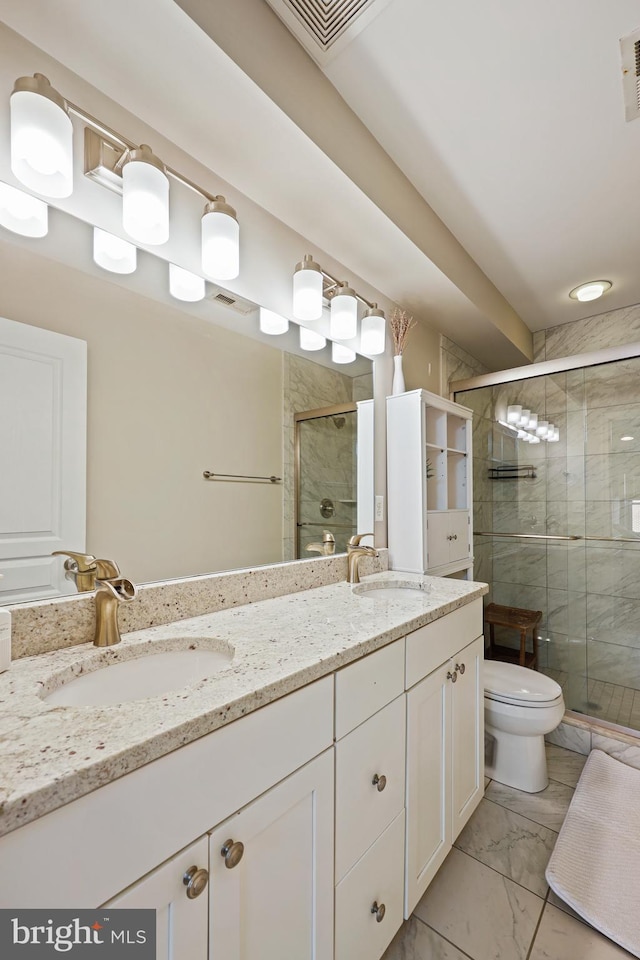 bathroom with marble finish floor, a sink, toilet, and a shower stall