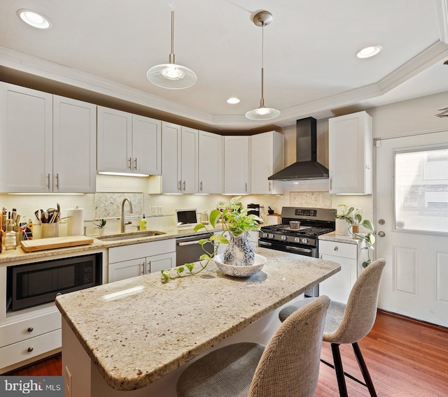 kitchen with wall chimney exhaust hood, decorative light fixtures, stainless steel appliances, white cabinetry, and a sink