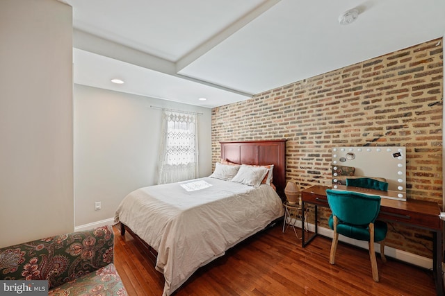 bedroom featuring baseboards, brick wall, and wood finished floors