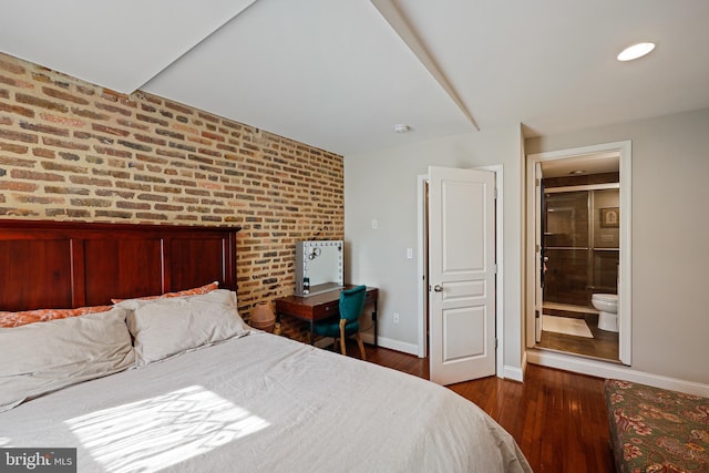 bedroom featuring ensuite bath, brick wall, baseboards, and dark wood-style flooring