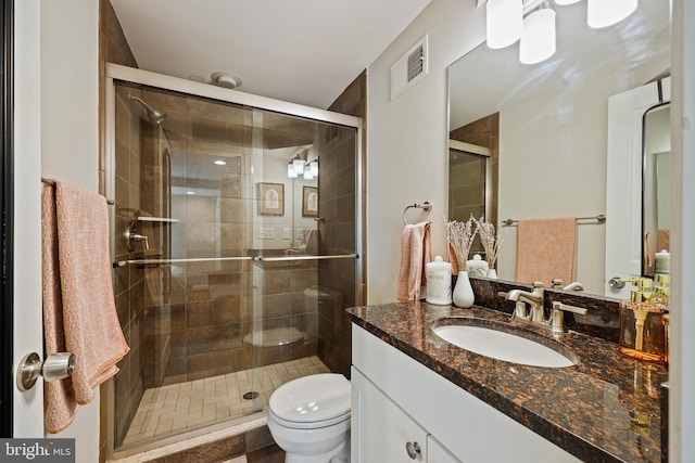 bathroom with toilet, a stall shower, visible vents, and vanity