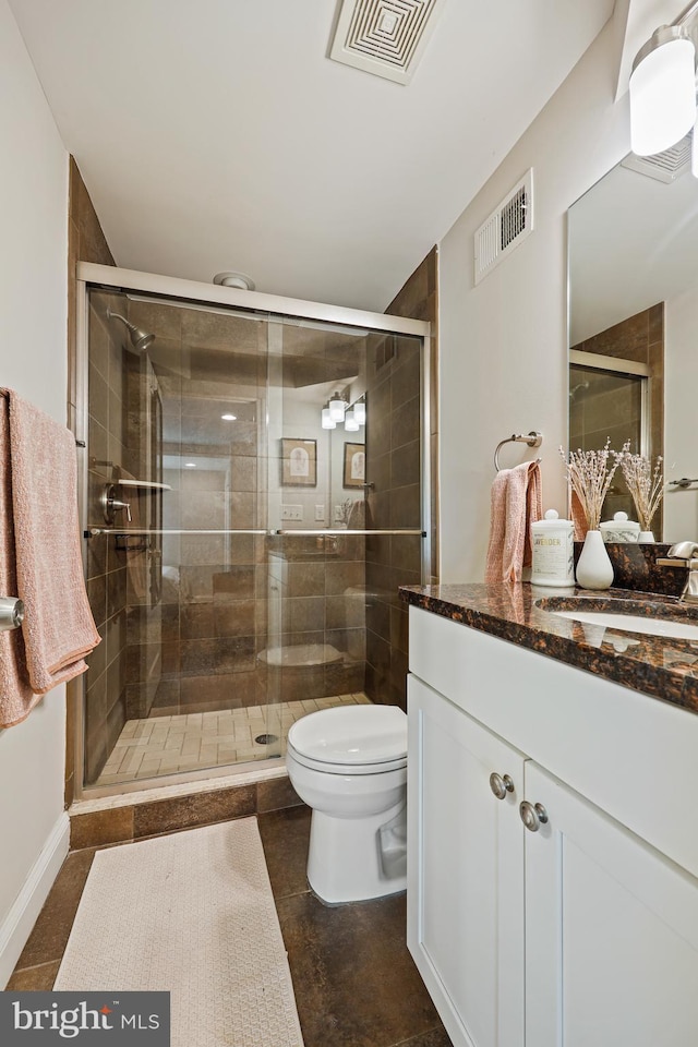 bathroom featuring toilet, a stall shower, and visible vents