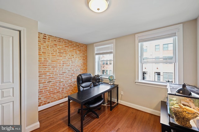 office space featuring brick wall, baseboards, and wood finished floors