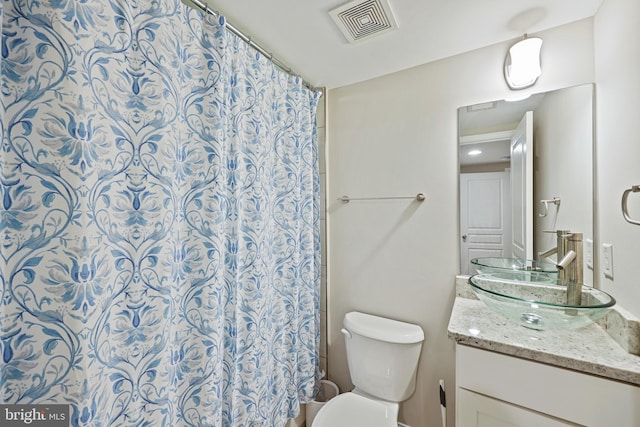 bathroom featuring a shower with shower curtain, visible vents, vanity, and toilet