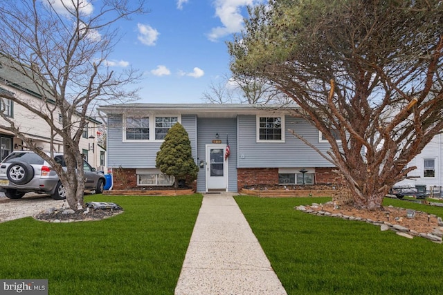 split foyer home featuring a front lawn and brick siding