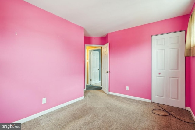 unfurnished bedroom with light carpet, baseboards, and a closet