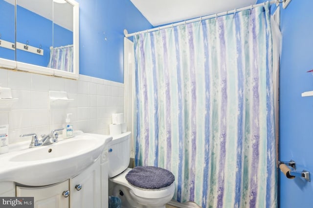 bathroom with toilet, curtained shower, a sink, and tile walls