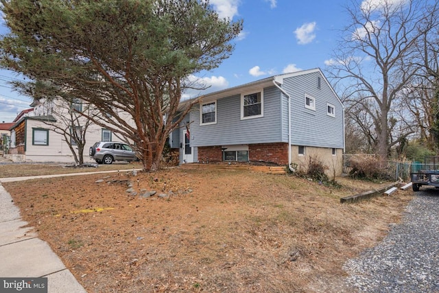 view of front of house featuring brick siding and fence