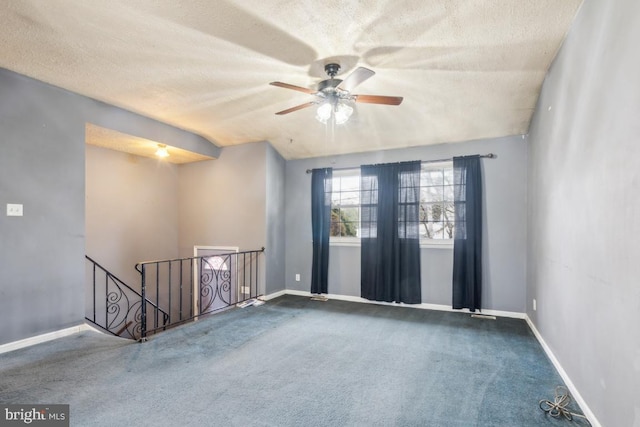 spare room featuring a textured ceiling, carpet, and baseboards