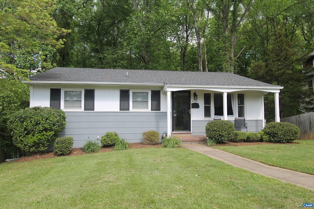 ranch-style home featuring a shingled roof, a front yard, and fence