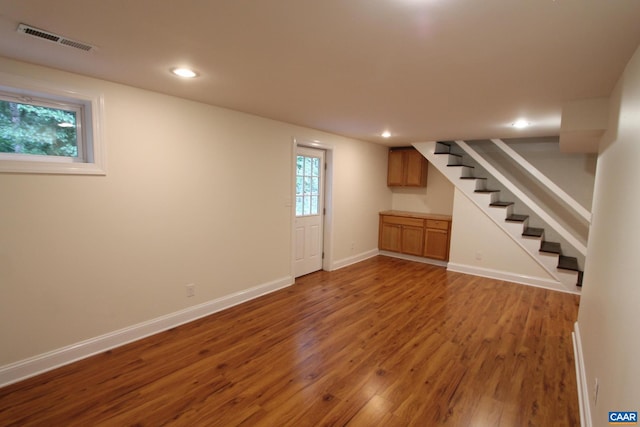 below grade area featuring baseboards, visible vents, wood finished floors, stairs, and recessed lighting