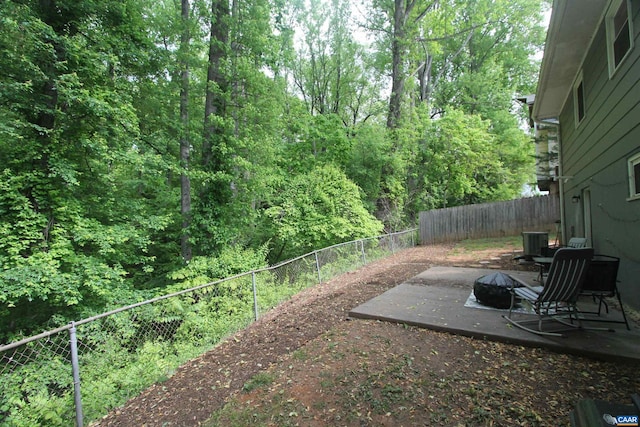 view of yard featuring an outdoor fire pit, a fenced backyard, central AC unit, and a patio