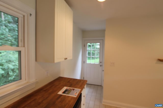 kitchen featuring white cabinets, wood counters, and baseboards