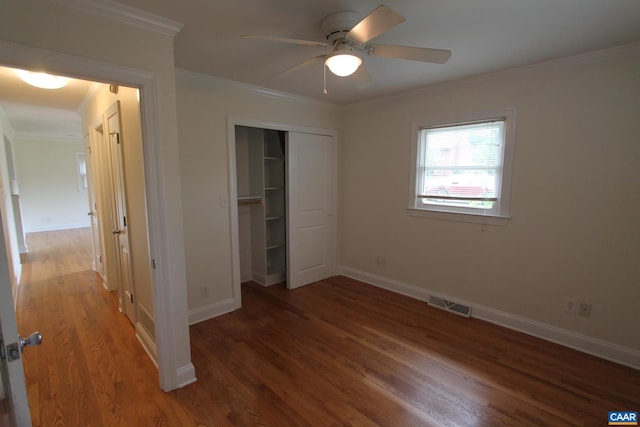 unfurnished bedroom featuring baseboards, visible vents, ornamental molding, wood finished floors, and a closet