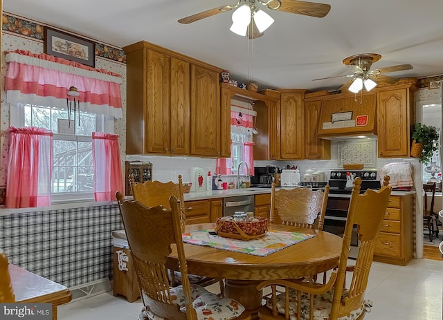 kitchen with appliances with stainless steel finishes, a wealth of natural light, brown cabinetry, and light countertops