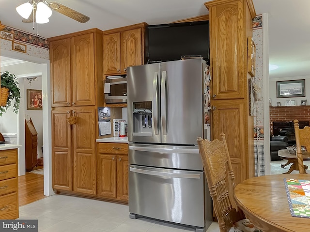 kitchen with stainless steel appliances, brown cabinets, light countertops, and a ceiling fan