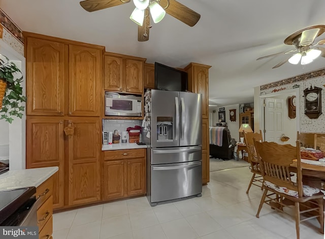 kitchen featuring stainless steel appliances, light countertops, a ceiling fan, and brown cabinets