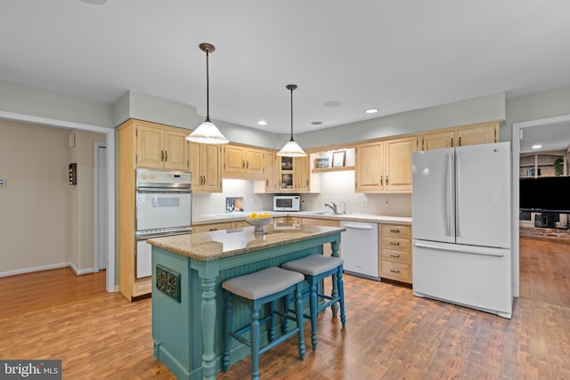 kitchen featuring a center island, a breakfast bar area, light brown cabinetry, glass insert cabinets, and white appliances