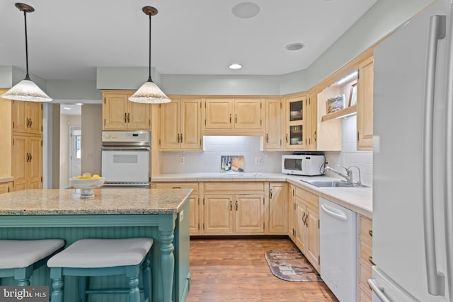 kitchen featuring white appliances, a center island, decorative backsplash, and light brown cabinetry