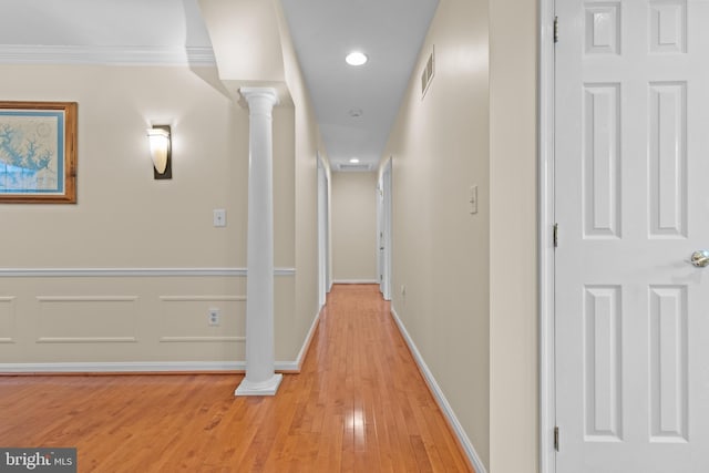 hallway featuring decorative columns, crown molding, visible vents, light wood-style floors, and baseboards