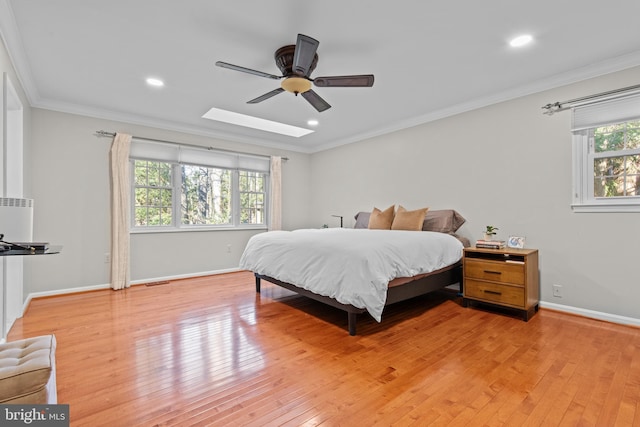 bedroom featuring light wood-style floors, a skylight, crown molding, and baseboards