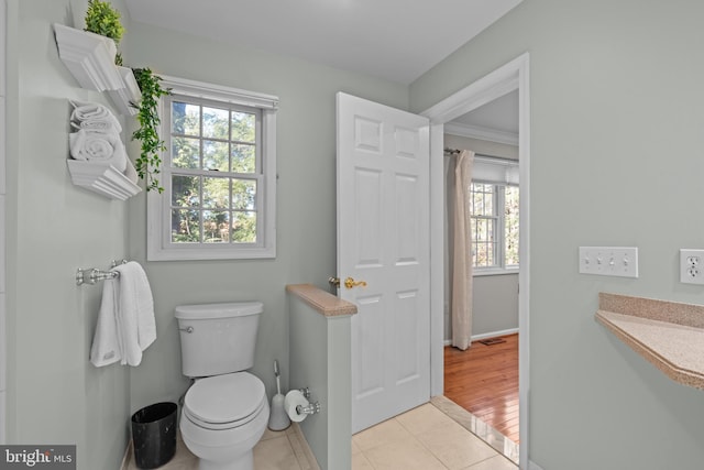 bathroom with baseboards, visible vents, toilet, and tile patterned floors