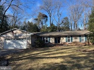 ranch-style home featuring driveway, an attached garage, and a front yard