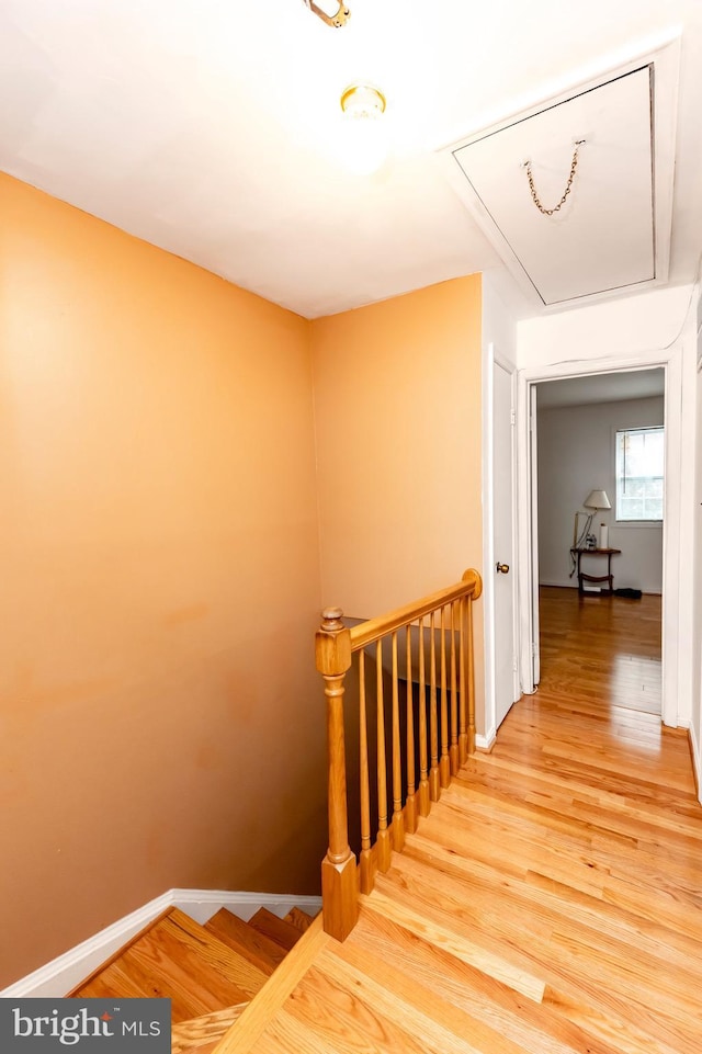 stairs with attic access, baseboards, and wood finished floors