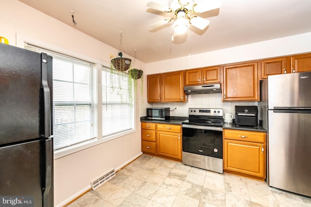 kitchen featuring dark countertops, visible vents, brown cabinetry, under cabinet range hood, and black appliances