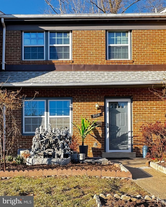 view of front facade with a shingled roof and brick siding