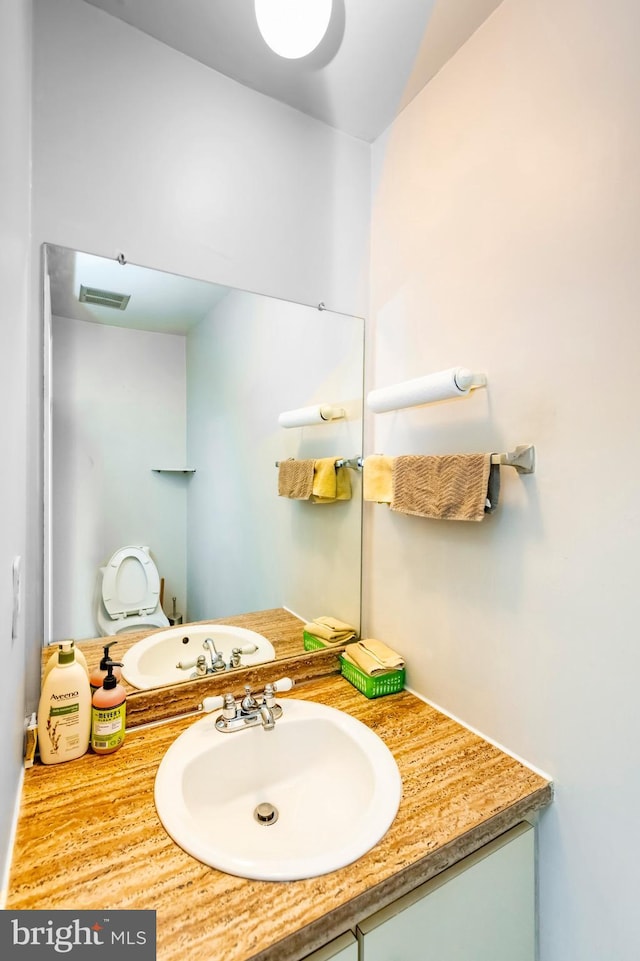 bathroom with visible vents, vanity, and toilet