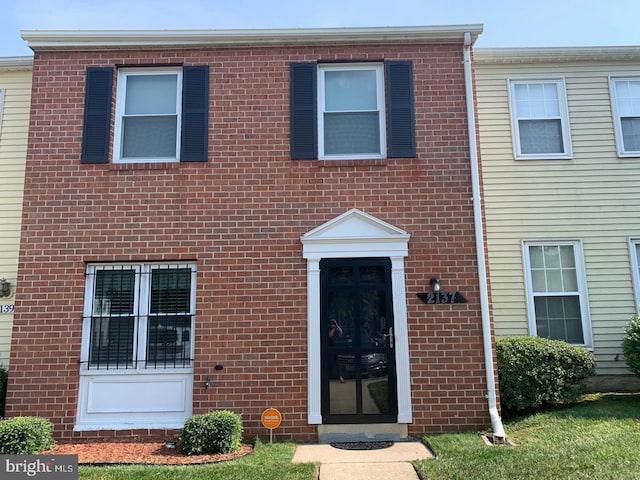 multi unit property featuring brick siding and a front lawn