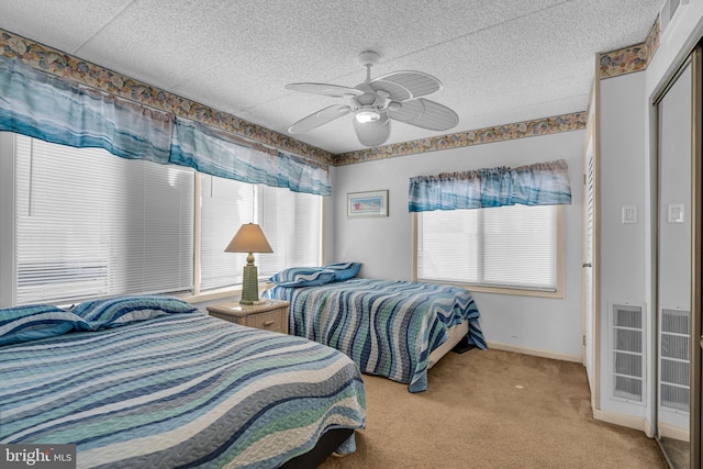 bedroom featuring light carpet, ceiling fan, a textured ceiling, and baseboards