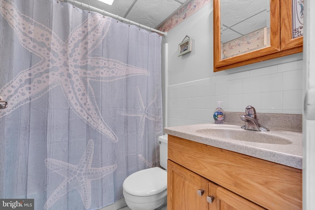 full bath with vanity, toilet, and tile walls